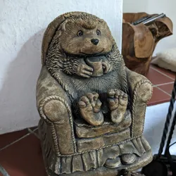 A wooden figure of a happy hedgehog sitting on an armchair