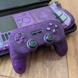 A game controller and the Steam Deck back plate with a translucent purple shell each