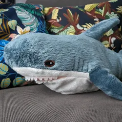 A blue shark as plush toy in front of two cushions