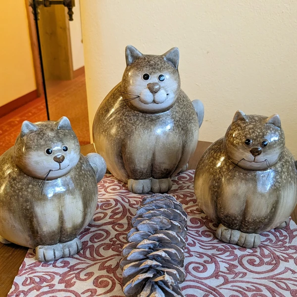 Three statues of fat cats on a table as decoration