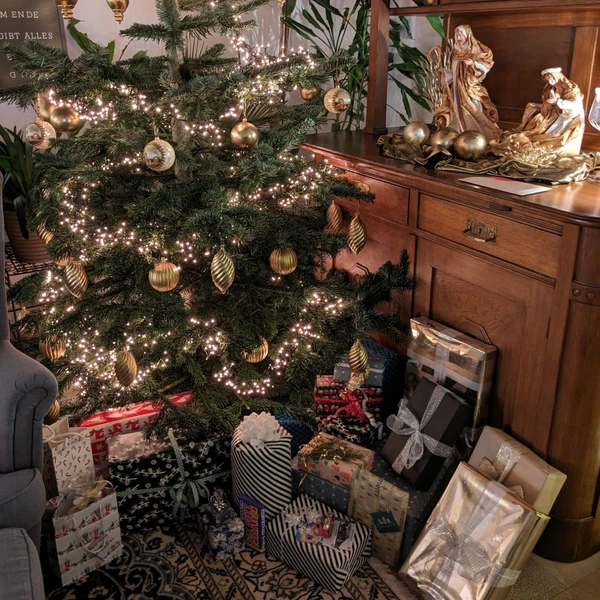 A decorated, shining Christmas tree with lots of presents underneath