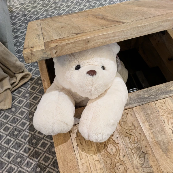 A large plush polar bear wedged in the lid of a wooden chest