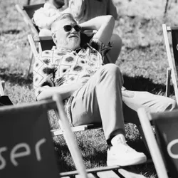A man with sunglasses lying on a lounger in a meadow